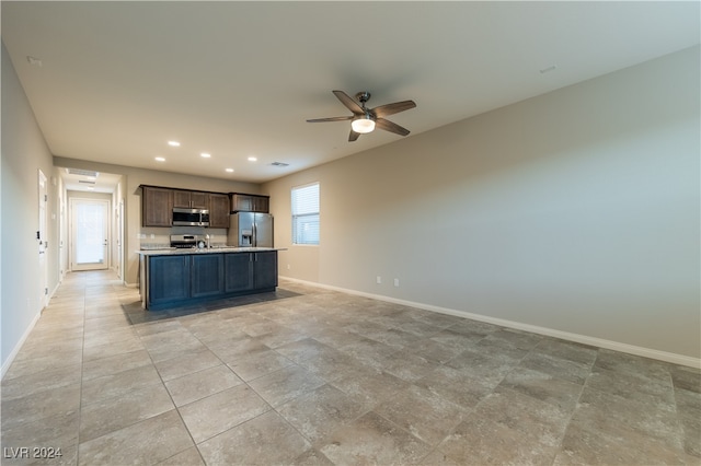 kitchen with a center island with sink, dark brown cabinetry, stainless steel appliances, and ceiling fan