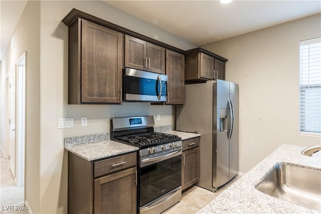 2664 Chinaberry Hill St, Laughlin, NV 89029 - kitchen featuring appliances with stainless steel finishes, a sink, dark brown cabinetry, and light stone counters