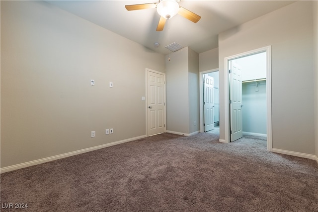 unfurnished bedroom featuring a spacious closet, ceiling fan, a closet, and carpet