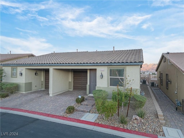 2664 Chinaberry Hill St, Laughlin, NV 89029 - view of front of house with a tiled roof, an attached garage, stucco siding, decorative driveway, and central AC