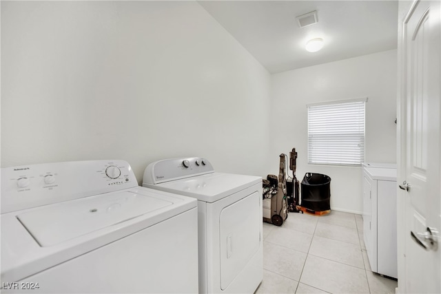 clothes washing area with washing machine and clothes dryer and light tile patterned floors