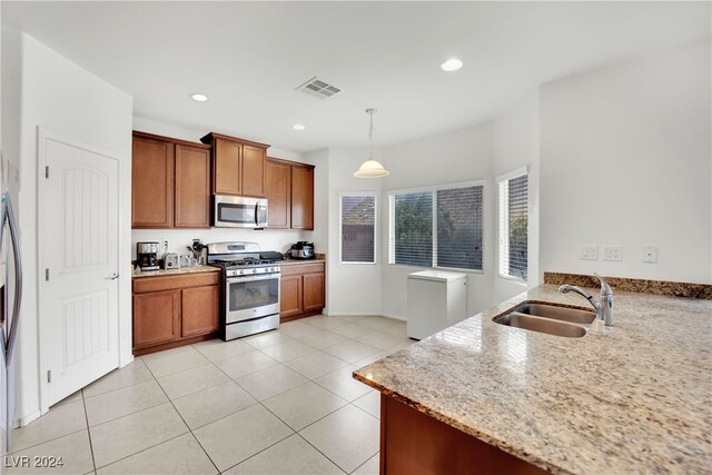 kitchen featuring sink, hanging light fixtures, stainless steel appliances, light stone counters, and light tile patterned floors