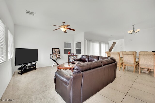 living room featuring ceiling fan with notable chandelier and light tile patterned floors