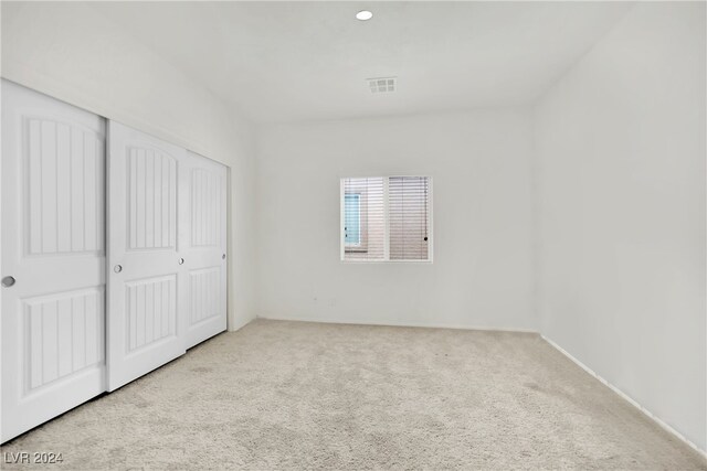 unfurnished bedroom featuring a closet and light colored carpet