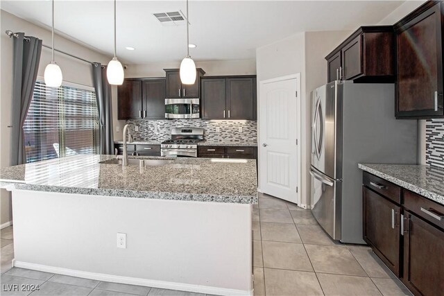 kitchen with backsplash, sink, stainless steel appliances, and a kitchen island with sink