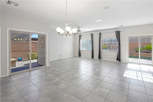 tiled spare room featuring ceiling fan with notable chandelier and a healthy amount of sunlight