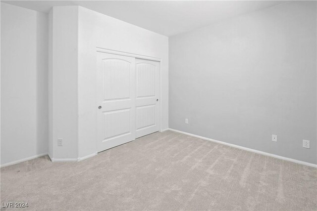 unfurnished bedroom with light carpet and a closet