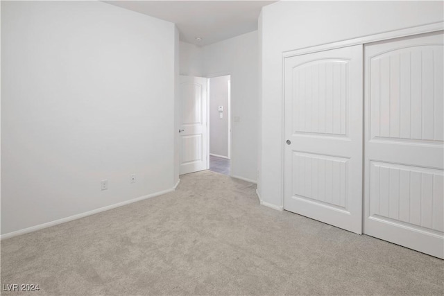 unfurnished bedroom with light colored carpet and a closet