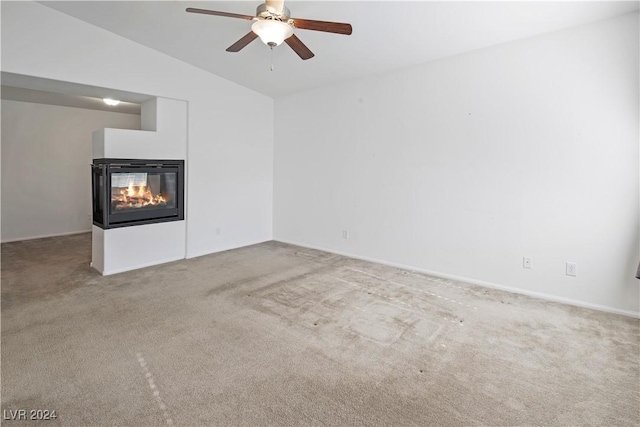 unfurnished living room featuring a multi sided fireplace, light carpet, ceiling fan, and lofted ceiling