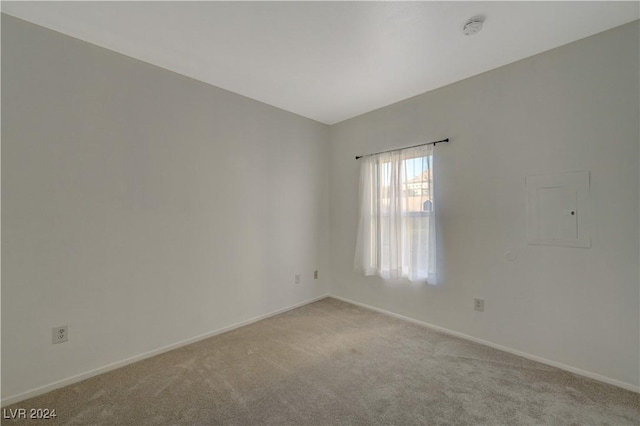 spare room with baseboards, electric panel, and light colored carpet
