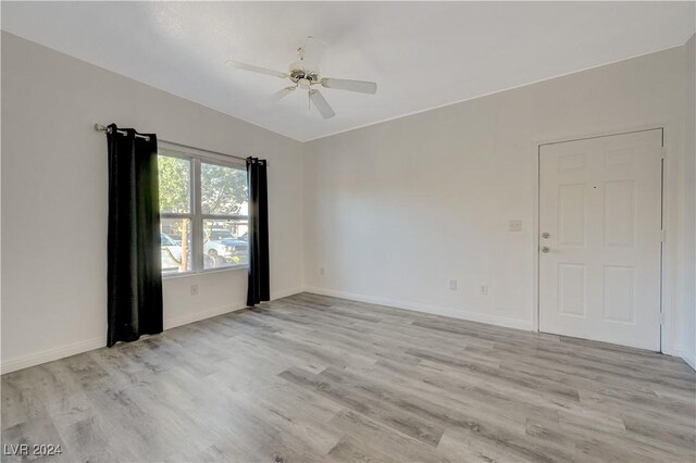 unfurnished room with baseboards, ceiling fan, and light wood-style floors