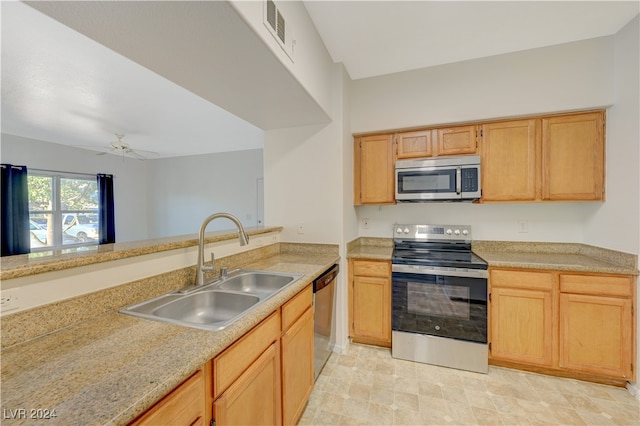 kitchen featuring ceiling fan, appliances with stainless steel finishes, light brown cabinetry, and sink