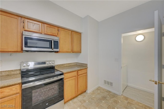 kitchen with light countertops, stainless steel appliances, baseboards, visible vents, and light brown cabinets