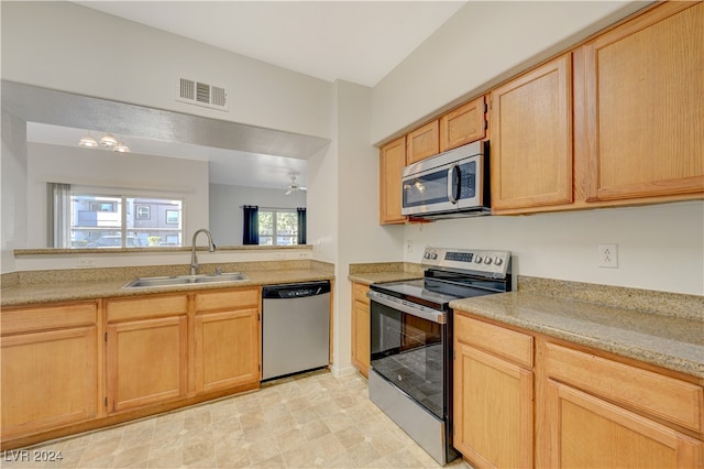 kitchen with appliances with stainless steel finishes, light brown cabinetry, and sink