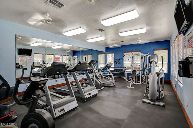 exercise room with ceiling fan and a textured ceiling