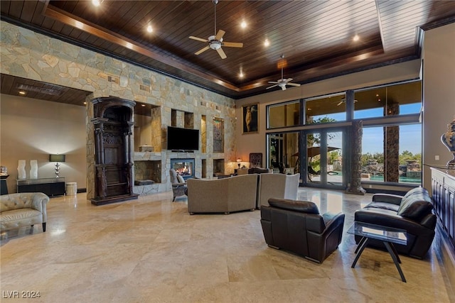 living room featuring a tray ceiling, a fireplace, wood ceiling, and a high ceiling