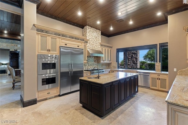 kitchen featuring a center island with sink, light stone counters, ornamental molding, and appliances with stainless steel finishes