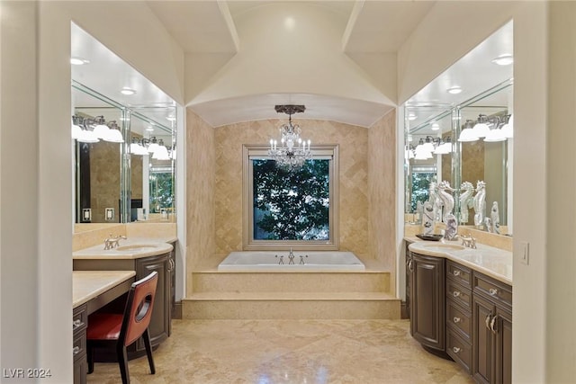 bathroom with a notable chandelier, vanity, and tiled tub