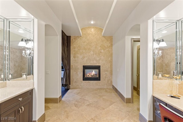 bathroom featuring vanity, vaulted ceiling, and a tiled fireplace