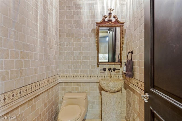 bathroom featuring toilet, sink, and tile walls