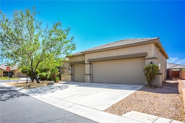 view of front of property featuring driveway, a tiled roof, an attached garage, fence, and stucco siding