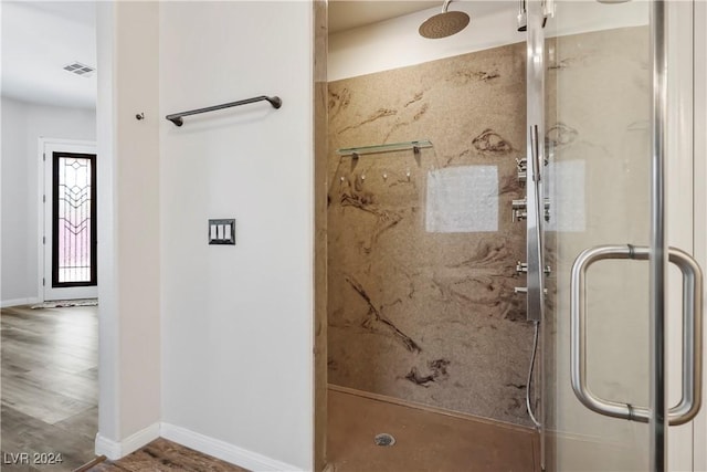 bathroom featuring wood finished floors, a marble finish shower, visible vents, and baseboards