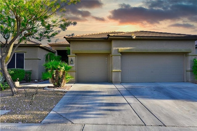 view of front of property featuring a garage, concrete driveway, a tile roof, and stucco siding