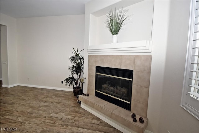 interior details featuring baseboards, wood finished floors, and a tile fireplace