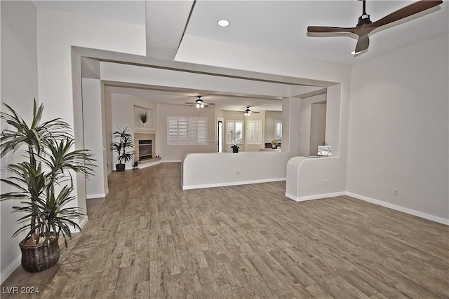 unfurnished living room featuring a glass covered fireplace, wood finished floors, and baseboards