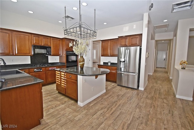 kitchen featuring light wood-type flooring, black appliances, visible vents, and a sink