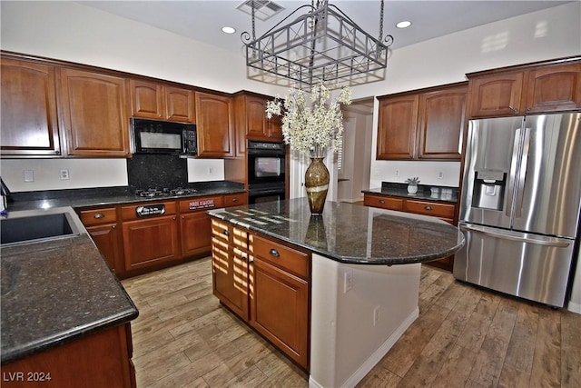 kitchen featuring black appliances, a sink, visible vents, and light wood-style floors