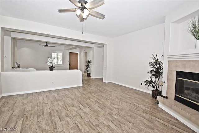 unfurnished living room with a ceiling fan, a fireplace, baseboards, and wood finished floors