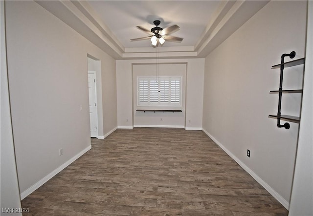 spare room featuring a ceiling fan, a raised ceiling, baseboards, and dark wood-style flooring