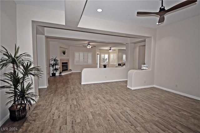 unfurnished living room with a glass covered fireplace, baseboards, and wood finished floors