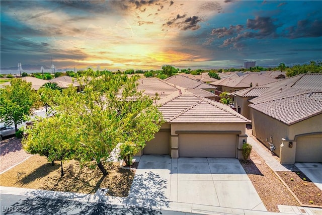 view of front of house featuring a garage, driveway, a tiled roof, and stucco siding