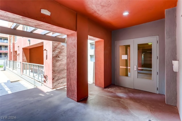 hallway featuring french doors and concrete flooring