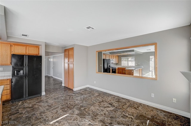 kitchen with range with electric cooktop, kitchen peninsula, and black fridge