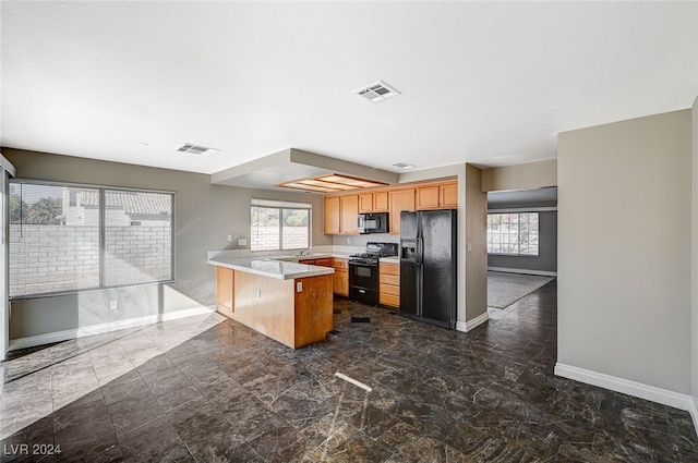 kitchen with a breakfast bar area, black appliances, and kitchen peninsula