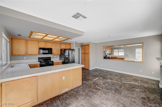 kitchen with tile countertops, sink, black appliances, and kitchen peninsula