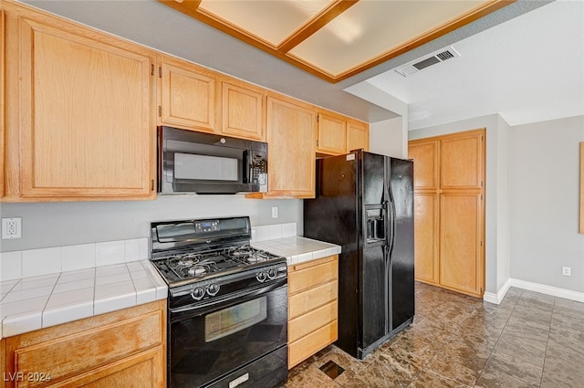 kitchen with light brown cabinets, tile counters, and black appliances