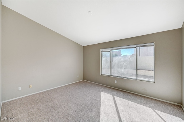 spare room featuring lofted ceiling and light colored carpet