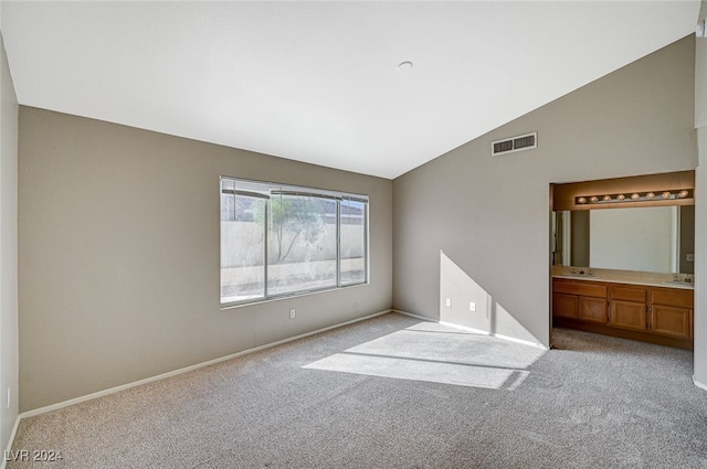 spare room featuring sink, vaulted ceiling, and light colored carpet