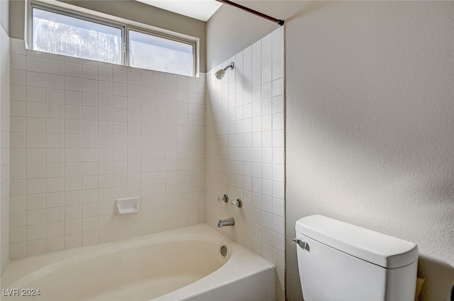 bathroom with toilet and tiled shower / bath