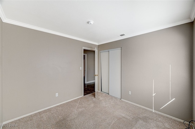 unfurnished bedroom with crown molding, carpet floors, and a closet