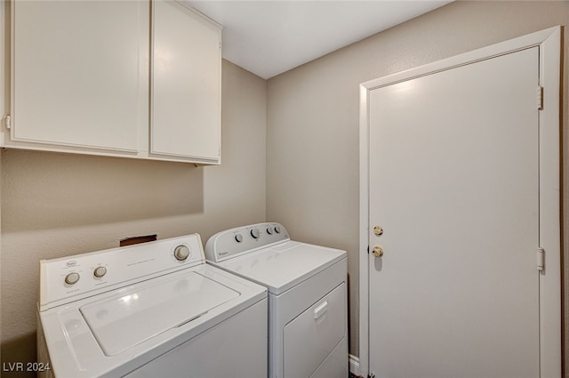 clothes washing area with cabinets and washer and clothes dryer