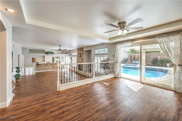 empty room featuring a raised ceiling, ceiling fan, hardwood / wood-style floors, and a textured ceiling