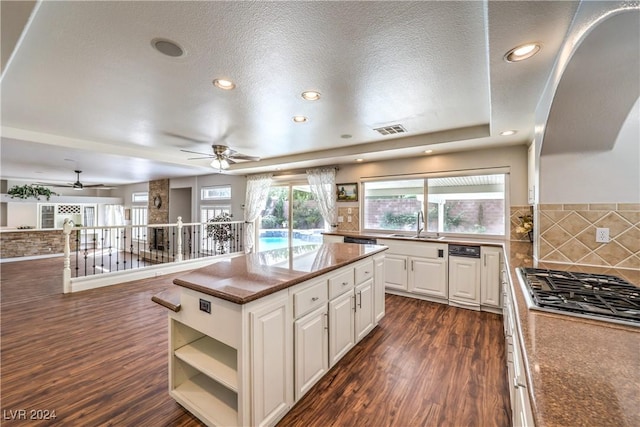 kitchen featuring white cabinetry, ceiling fan, stainless steel gas cooktop, dark hardwood / wood-style flooring, and a textured ceiling