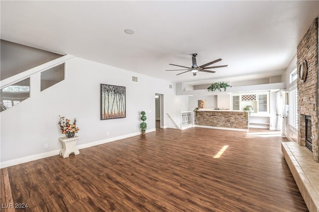 unfurnished living room with a fireplace, ceiling fan, and dark wood-type flooring