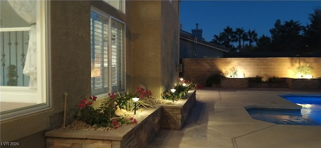 pool at twilight with a patio area