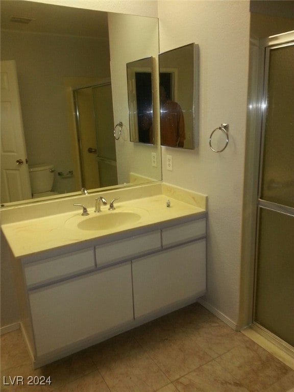 bathroom with tile patterned flooring, toilet, and a shower with door